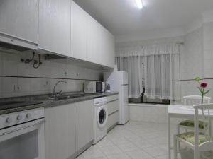 eine weiße Küche mit einer Spüle und einem Geschirrspüler in der Unterkunft Ar Puro III in Viana do Castelo