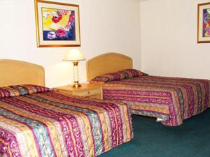 a hotel room with two beds and a table with a lamp at El Rancho Motel Lodi in Lodi