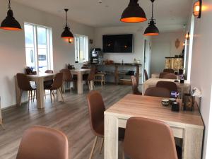 a living room with tables and chairs and a kitchen at Hrafnavellir Guest House in Hrafnavellir