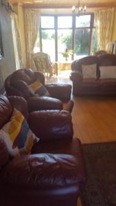 a living room with leather couches and a couch at Tulla Villa Self Catering in Riverstown