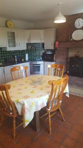 una cocina con mesa con 4 sillas y una cocina con reloj en Tulla Villa Self Catering, en Riverstown