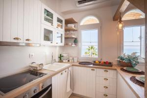 a kitchen with white cabinets and a sink and two windows at Nautilus Sea View Suite 6 in Pefkohori