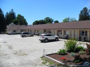 two cars parked in a parking lot in front of a building at Forest Plaza Motel in Mount Forest