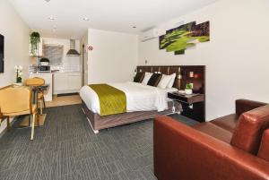 Un dormitorio con una cama y un sofá y una cocina. en Newlands Court Motel, en Wellington