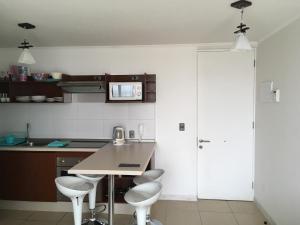 une cuisine avec une table et quatre tabourets dans l'établissement Departamento Coquimbo a pasos de la playa, à Coquimbo