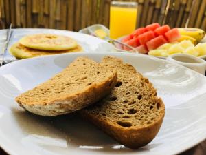 a white plate with bread and fruit on a table at El Homestay Bali in Nusa Dua +44 photos