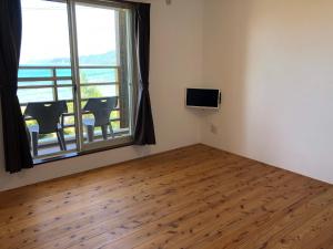 una camera con una grande finestra e un tavolo con sedie di Guest room Halemakana ad Amami