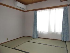 an empty room with a window with blue curtains at Minshuku Nakano in Fujiyoshida