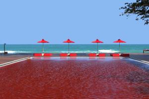 una piscina con sedie rosse e ombrelloni sulla spiaggia di The Library a Chaweng Beach