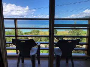 due sedie davanti a una finestra che guarda fuori l'oceano di Guest room Halemakana ad Amami