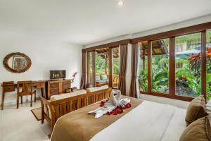 a bedroom with a bed and a table with a desk at Jati Cottage in Ubud +37 photos