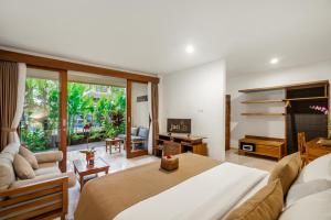 a living room filled with furniture and a large window at Jati Cottage in Ubud