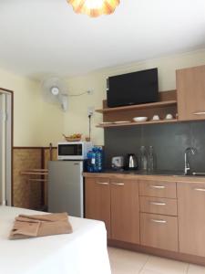 a kitchen with wooden cabinets and a microwave at Pink Kangaroo Bungalows in Ko Kood