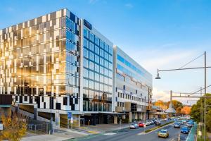 ein großes Glasgebäude in einer Stadtstraße mit Autos in der Unterkunft Mantra Albury in Albury