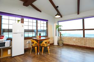 cocina con mesa y sillas en una habitación con ventanas en Gyeryonggil Pension en Jeju