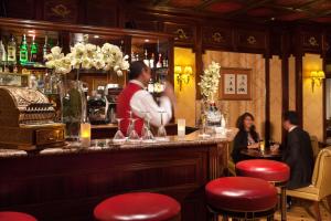 Un uomo in piedi dietro un bar in un ristorante di Hôtel Mayfair Paris a Parigi