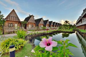 eine Reihe von Häusern und ein Teich mit einer rosa Blume in der Unterkunft Island Paradise Resort Club in Koror