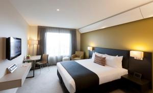 a hotel room with a large bed and a desk at Sudima Auckland Airport in Auckland