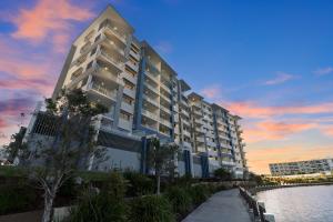a large white building next to a body of water at Aquarius Kawana in Kawana Waters