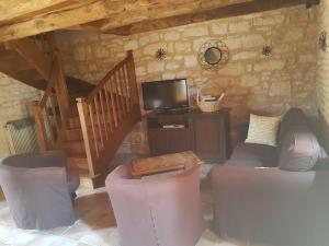 a living room with chairs and a tv and a staircase at Champagnac in Borrèze