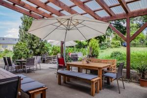 a patio with a wooden table and an umbrella at Hotel Grauleshof in Aalen