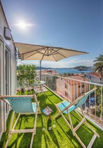 einen Balkon mit 2 Stühlen und einem Sonnenschirm in der Unterkunft Nikky’s BLUE DREAM Apartment in Mali Lošinj