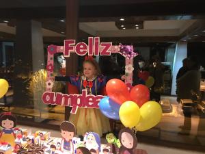una niñita parada junto a un cartel con globos en Hotel HF en Farellones