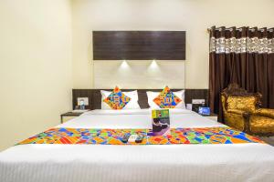 a bedroom with two beds and a chair at FabHotel Crown Suites in Bangalore