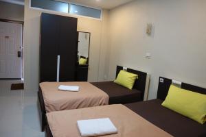 a small room with two beds and a mirror at Ratchanee Place in Chaiyaphum