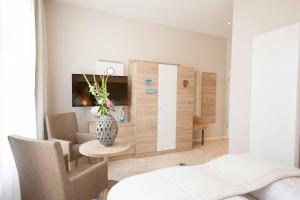 a room with a bed and a vase of flowers at Ostseehotel Warnemünde in Warnemünde +20 photos