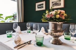 un vaso di fiori seduto su un tavolo con gli occhiali di Strandhotel Sille a Reifnitz