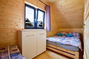 a small bedroom with a bed in a wooden cabin at Sarbinowo Prestige - Ekskluzywne domki nad morzem in Sarbinowo +44 photos