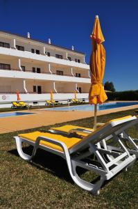 un fauteuil et un parasol à côté d'un bâtiment dans l'établissement Solgarve, à Quarteira