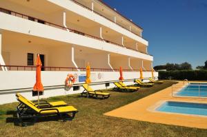 a hotel with chairs and umbrellas next to a swimming pool at Solgarve in Quarteira