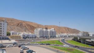 eine belebte Autobahn in einer Stadt mit Gebäuden und einem Berg in der Unterkunft Al Jisr Hotel in Muscat
