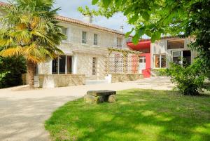 a stone bench sitting in the grass in front of a building at La Ferme du Marais Poitevin - Chambre d'hôtes in Benet