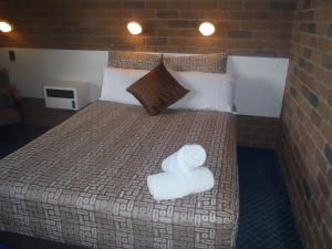 a bedroom with a bed with two towels on it at Cattleman's Rest Motor Inn in Charters Towers