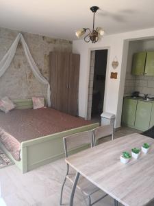 a bedroom with a bed and a table and a kitchen at Szitakötő Apartman in Demjén