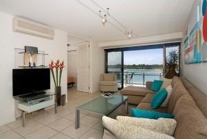 een woonkamer met een bank en een tv bij Commodore Apartments in Noosa Heads