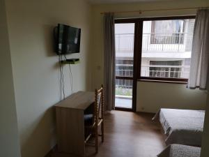 Habitación con mesa, TV y ventana. en Alfa Guest House - Free Parking, en Varna