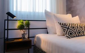 a bed with white pillows and a lamp on a table at Prima Tel Aviv Hotel in Tel Aviv