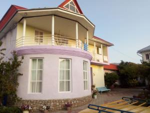 a yellow and pink house with a balcony at Prestige Guest house in Cholpon-Ata