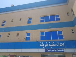 a building with a sign on the side of it at Sanabel Al Mish'an Furnished Units in Al Jithāmīyah