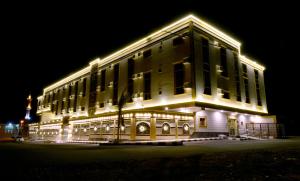 un grand bâtiment avec des lumières allumées la nuit dans l'établissement Marina Hotel, à Rayyis