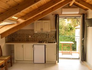 a kitchen with white cabinets and a door to a patio at Yasemi Rooms in Vasiliki