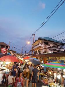 a group of people walking around a market with umbrellas at C.Samui Guesthouse in Lamai