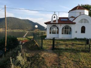 a white church with a fence next to a body of water at Agios Achillios in Agios Achillios