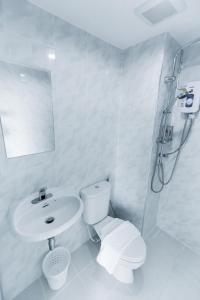 a white bathroom with a toilet and a sink at Kanyanat Boutique Hotel in Lampang