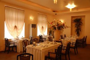 a banquet room with tables and chairs with white tablecloths at Sakhalin Sapporo Hotel in Yuzhno-Sakhalinsk