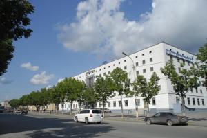 un edificio blanco con coches estacionados frente a él en Sakhalin Sapporo Hotel, en Yuzhno-Sakhalinsk